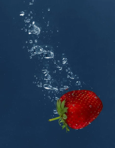 Fresa jugosa que cae en el agua —  Fotos de Stock