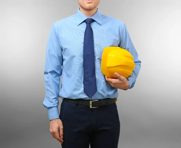 Knappe ingenieur met gele veiligheidshelm op lichte achtergrond — Stockfoto
