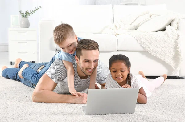 Padre con niños acostado con el ordenador portátil — Foto de Stock