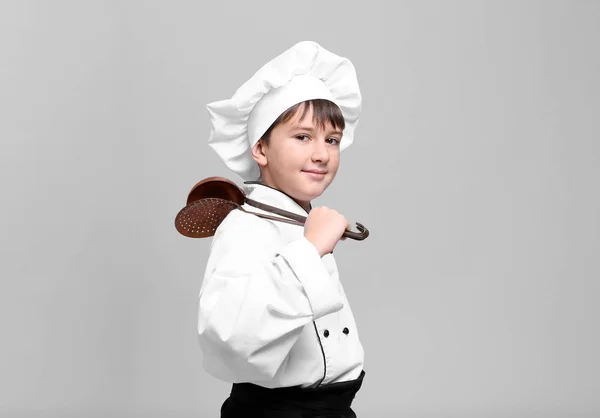 Lindo chico en uniforme de chef sobre fondo claro — Foto de Stock