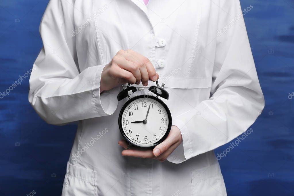 Doctor holding alarm clock 