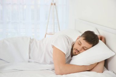 Adam yatakta uyuyor.