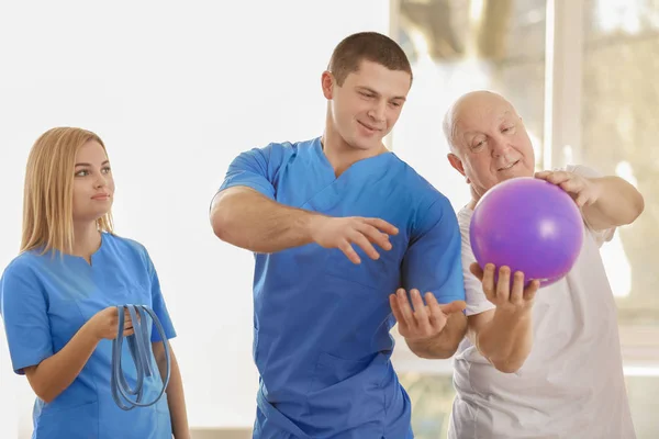 Fisioterapeuta que trabaja con pacientes de edad avanzada en clínica — Foto de Stock