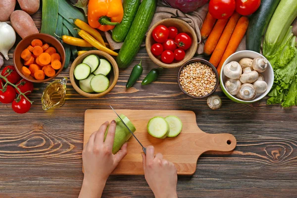 Vrouwelijke handen snijden squash aan tafel, bovenaanzicht — Stockfoto