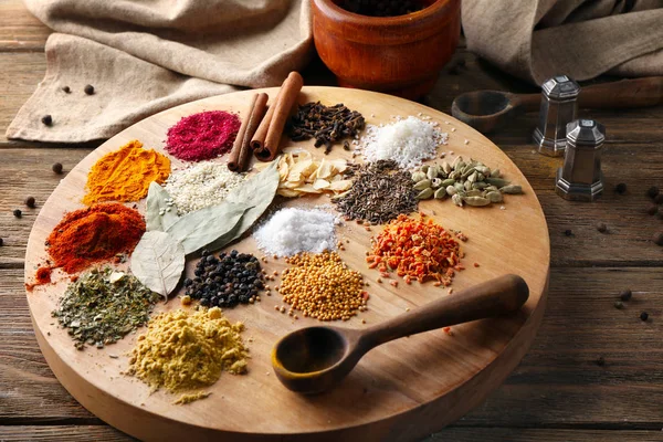 Tablero con diferentes especias aromáticas en mesa de madera — Foto de Stock