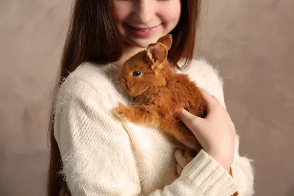 Cute girl holding rabbit on grey wall background — Stock Photo, Image