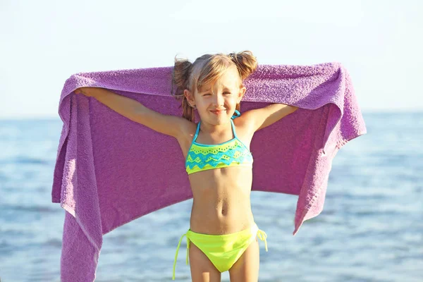 Menina bonito envolto em toalha na praia — Fotografia de Stock