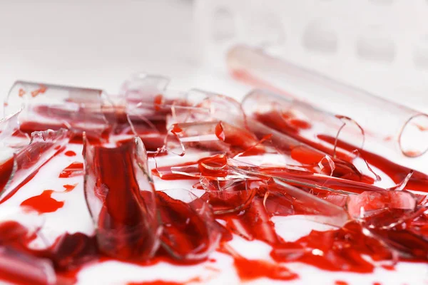 Broken test tubes with blood on white table — Stock Photo, Image