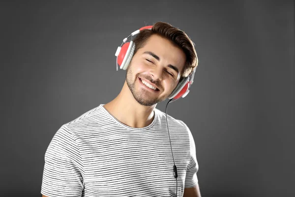 Емоційний чоловік з навушниками слухає музику на сірому фоні — стокове фото