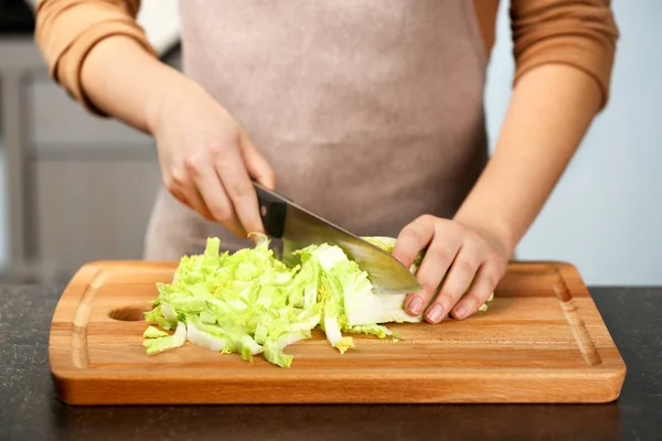 Руки женщины режут китайскую капусту за столом на кухне — стоковое фото