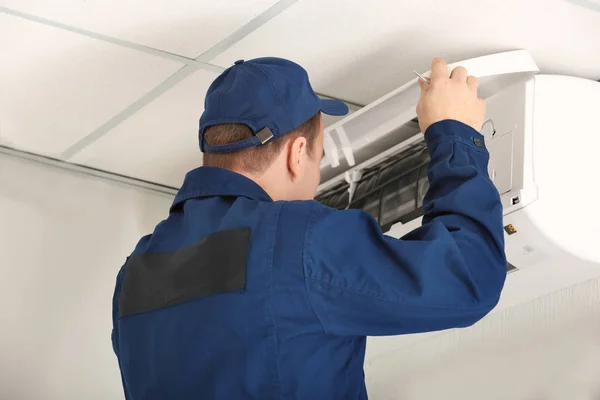 Werknemer verrichten onderhoud van airconditioner in kantoor — Stockfoto