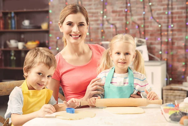 Madre joven con niños haciendo galletas en la mesa —  Fotos de Stock