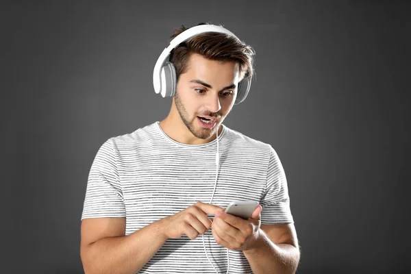 Hombre emocional con auriculares escuchando música sobre fondo gris —  Fotos de Stock