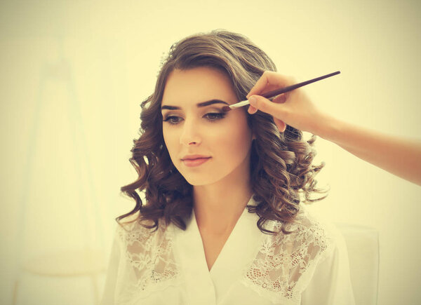 Makeup artist preparing bride