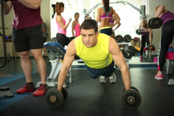 Jeune homme beau avec haltères formation dans la salle de gym — Photo