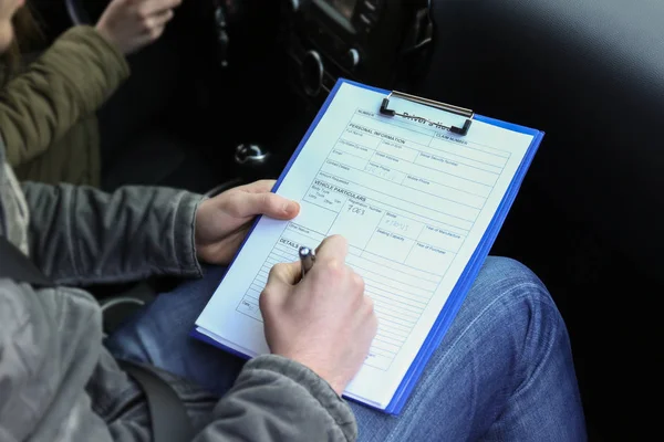 Instructor de la escuela de conducción que da examen mientras está sentado en el coche, primer plano — Foto de Stock