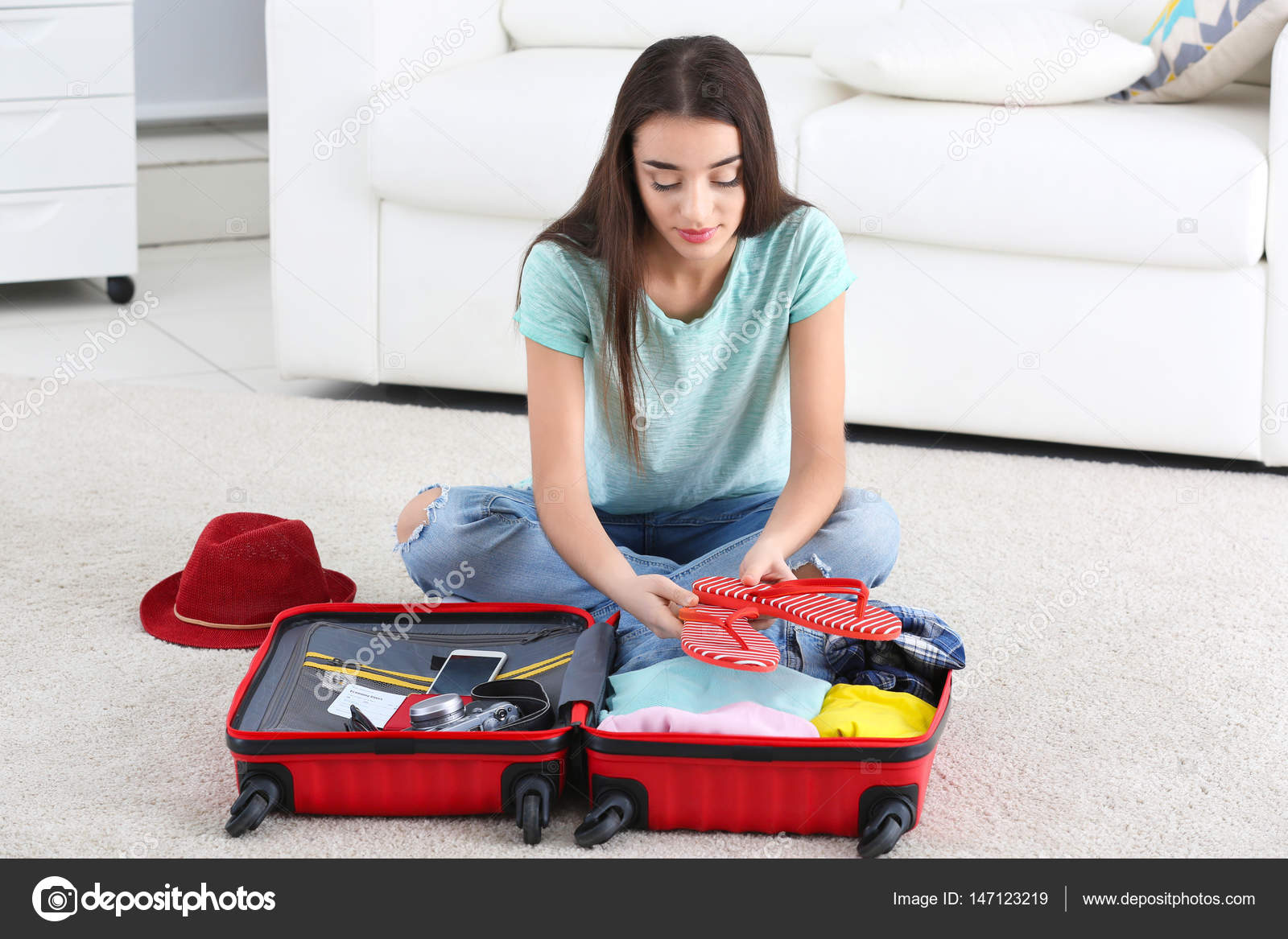 Young woman packing suitcase Stock Photo by belchonock 147123219
