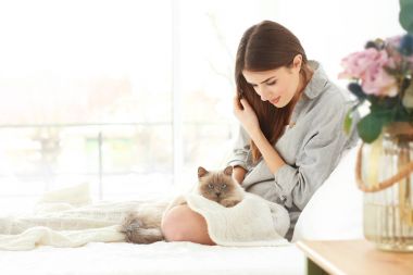 Güzel, genç bir kadın ve tatlı bir kedi evde dinleniyor.