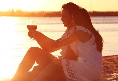 Gün batımı kumsalda romantik tarih olan şarap ile genç Çift