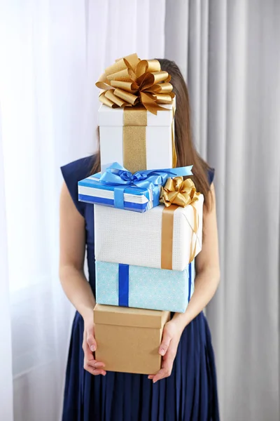 Vrouw met stapel geschenken thuis — Stockfoto