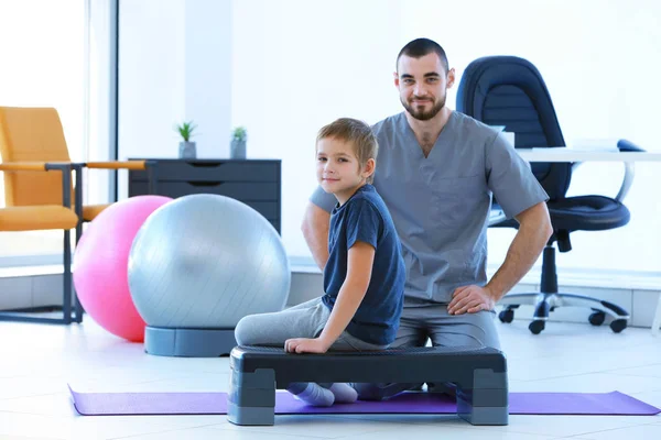 Fisioterapeuta y niño pequeño en la clínica —  Fotos de Stock