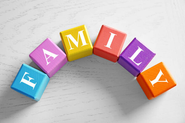 Colorful cubes with word FAMILY on wooden background