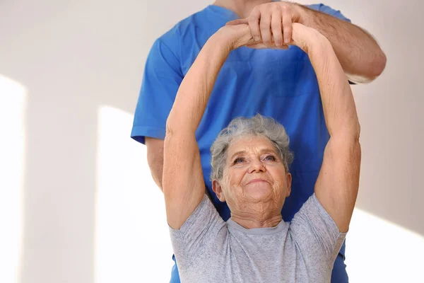 Fisioterapeuta que trabaja con pacientes de edad avanzada en clínica —  Fotos de Stock