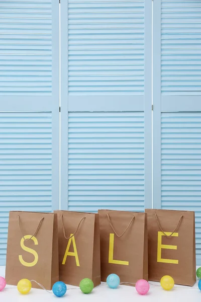 VENTA de palabra en bolsas de compras de papel contra fondo de pantalla plegable —  Fotos de Stock