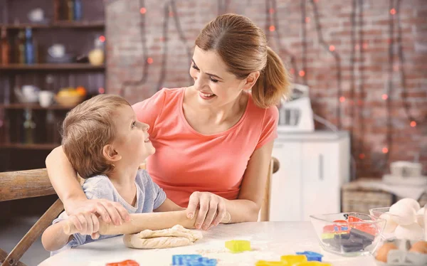 Jovem mãe com filho fazendo biscoitos na mesa — Fotografia de Stock