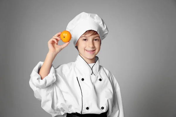 Jongen in chef-kok uniform met sinaasappel — Stockfoto