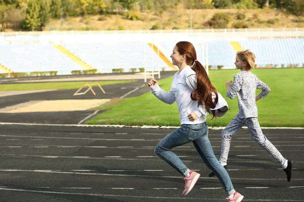 Niños deportivos corriendo en pista en el estadio — Foto de Stock