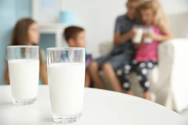 Vasos de leche sobre mesa blanca y fondo borroso —  Fotos de Stock