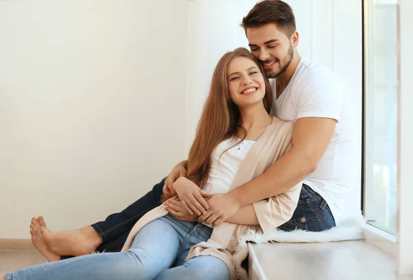 Joven pareja sentado cerca ventana — Foto de Stock