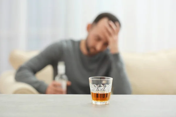 Glas mit Whisky auf dem Tisch und verschwommenem Mann im Hintergrund — Stockfoto