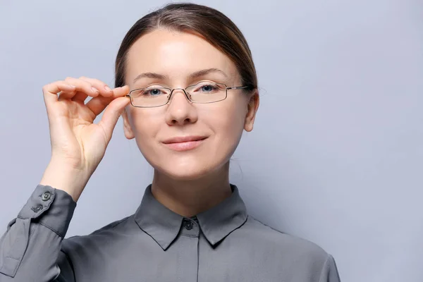 Jonge vrouw met bril op grijze achtergrond — Stockfoto