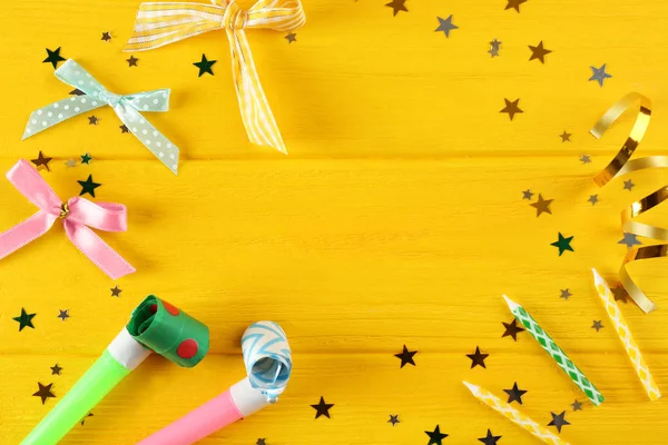 Confete brilhante e fife festivo em fundo amarelo de madeira — Fotografia de Stock