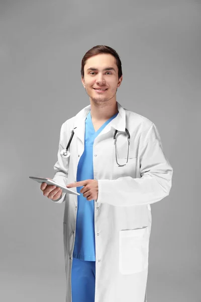 Young doctor with tablet on white background — Stock Photo, Image