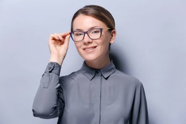 Gri arka plan üzerine gözlük ile genç kadın