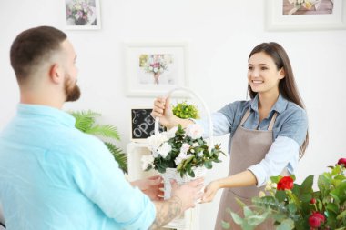 Genç ve güzel çiçekçi çiçek sepeti müşteriye vermek