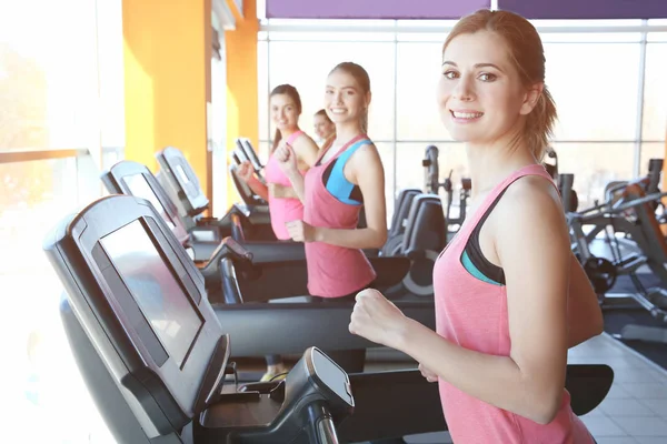 Jóvenes deportistas corriendo en cintas de correr en el gimnasio —  Fotos de Stock