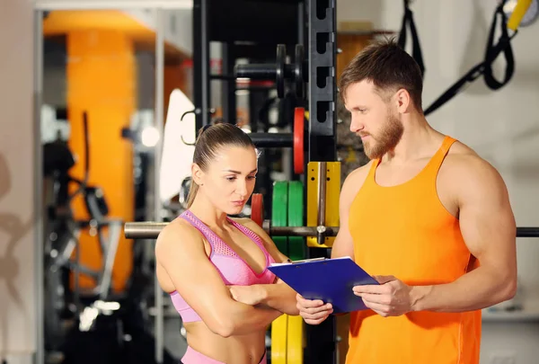 Ung kvinna med personlig tränare på gym — Stockfoto