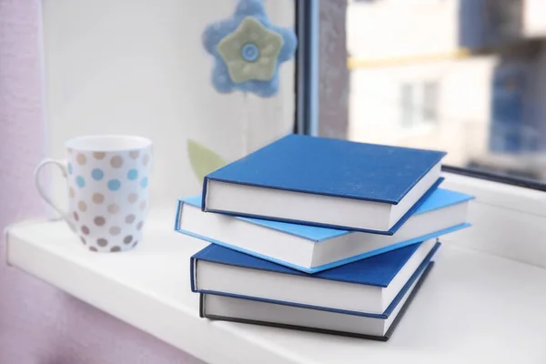 Stapel boeken en cup op de vensterbank — Stockfoto