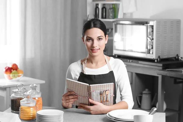 Jonge vrouw met kookboek — Stockfoto