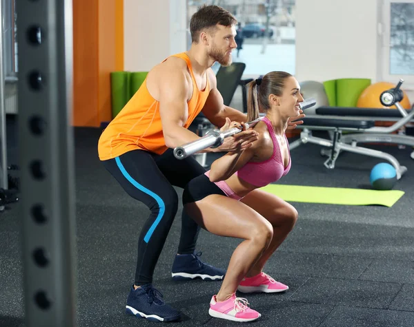 Vacker sportig kvinna träning med hennes tränare i gymmet — Stockfoto