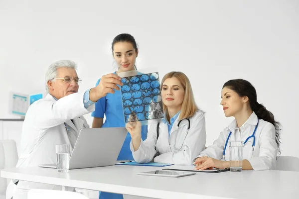 Team av läkare att utforska röntgenbilder vid bord — Stockfoto