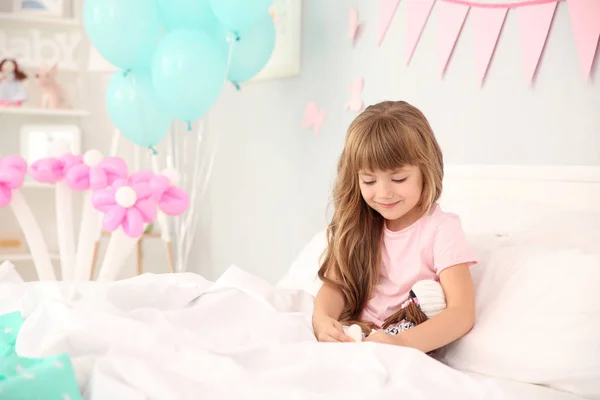 Menina de aniversário bonito com boneca na cama em casa — Fotografia de Stock