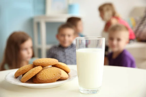 Glass of milk and cookies on white table and blurred background — Stock Photo, Image