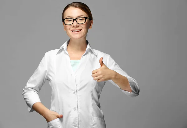 Jonge vrouw met bril op grijze achtergrond — Stockfoto