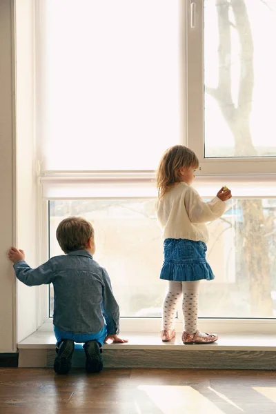 Leuke lieve kinderen in de buurt van grote venster thuis — Stockfoto