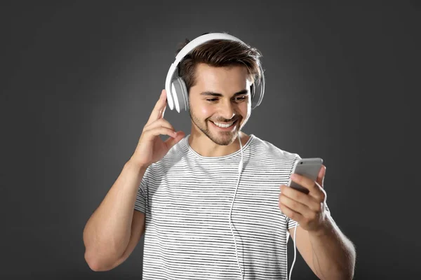 Эмоциональный человек с наушниками слушает музыку на сером фоне — стоковое фото